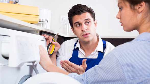 A washing machine technician that sent from home warranty company explain to a young woman the problem A washing machine technician that sent from home warranty company explain to a young woman the problem